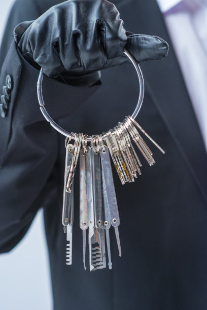 小偷用一只戴着黑色手套的手撬锁。一堆钥匙和锁在一个危险的陌生人手里。商业银行技术保护密码访问图片下载