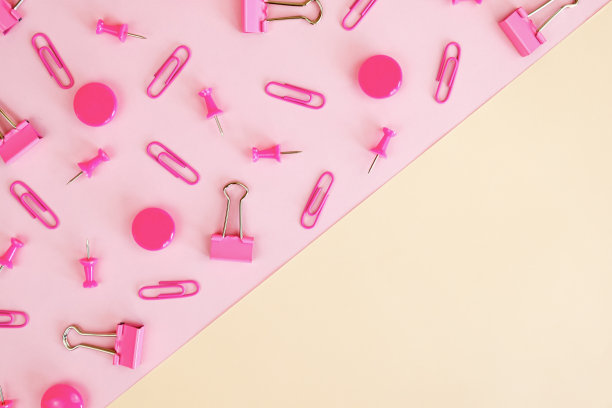粉红色和米色空白对角划分。散落在粉末状的回形针、图钉、活页夹图片下载