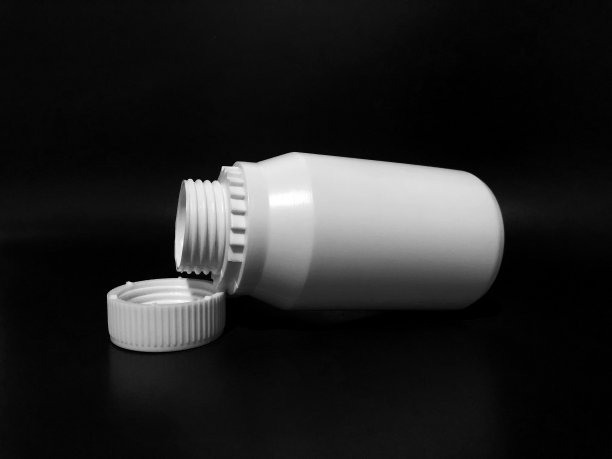 黑色背景上有一个白色的空塑料瓶子。图片下载