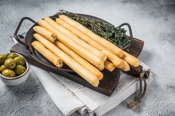 意大利格里西尼面包条放在钢盘里，配上香草。白色bakground。俯视图图片下载
