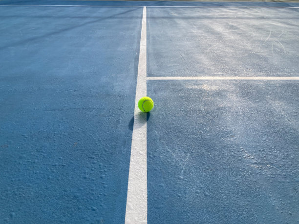 绿色的网球在蓝色网球场中间的白线上图片下载