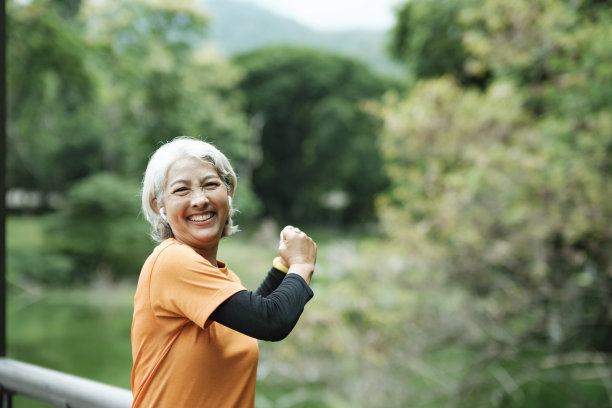 运动年长妇女伸展手臂在公园。图片下载