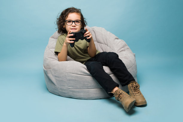 小男孩喜欢在蓝色背景下玩电子游戏图片下载