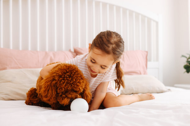 小女孩在床上和狗狗玩耍图片下载