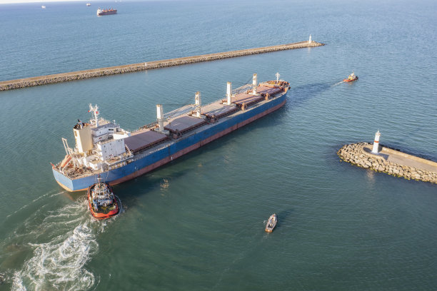 在海上拖着一艘大型货船的拖船。图片下载