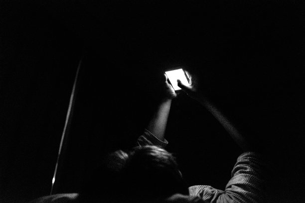 一个人晚上在黑暗的房间睡觉时操作智能手机的图片图片下载