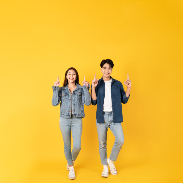一对年轻漂亮的亚洲夫妇用孤立的黄色背景呈现出复制空间的感觉图片下载
