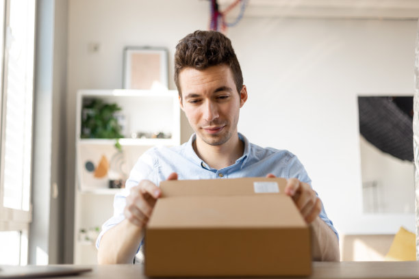 近距离的快乐惊喜的年轻人消费者捧着打开的纸盒坐在家里的沙发上，订购邮政快递的快递理念图片下载