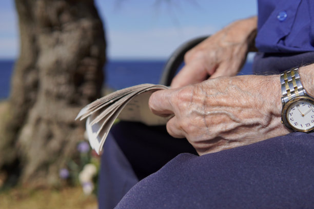 一个年长的男人指着报纸上的什么东西。图片下载