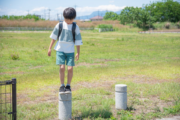 一个小学男孩在放学回家的路上停在公园里图片下载