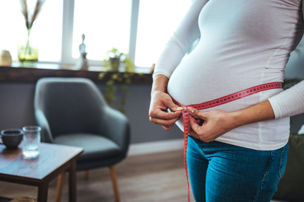 年轻漂亮的怀孕女孩在测量她的肚子图片下载