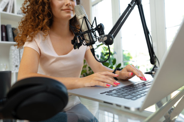 女视频博主看着笔记本电脑，用麦克风录制视频图片下载