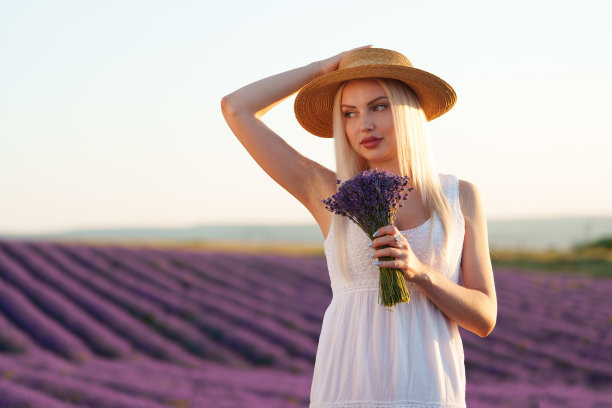 肖像迷人的金发女孩闻薰衣草花在薰衣草田图片下载