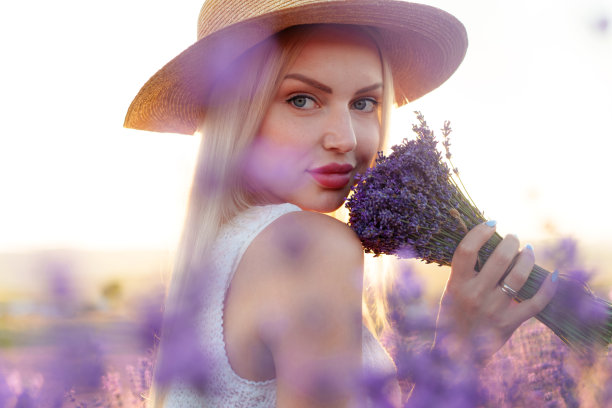 肖像迷人的金发女孩闻薰衣草花在薰衣草田图片下载