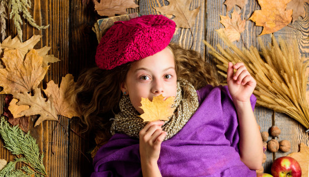 秋季时尚潮流。少女卧木背景落叶俯视图。针织配饰时尚细节。时尚小女孩明亮柔软的针织帽贝雷帽。秋季时尚配饰概念图片下载