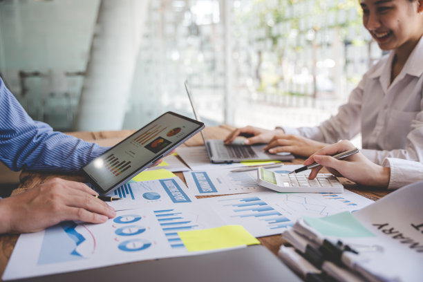 年轻的同事讨论业务和价格图表分析商务人士在桌子上伟大的现代联合办公办公室团队合作理念。图片下载