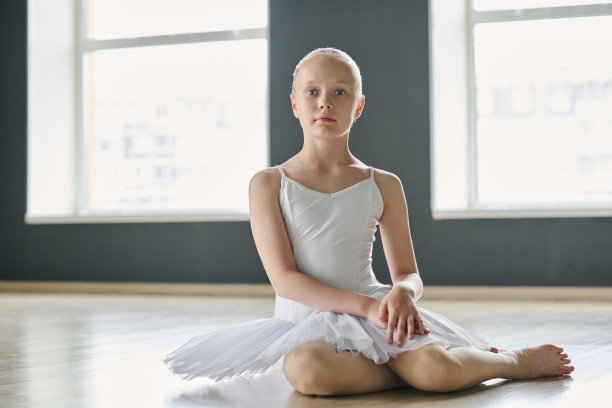 穿着白色芭蕾舞裙的青春期女学生坐在地板上看着镜头图片下载