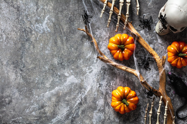 万圣节节日快乐的概念。万圣节装饰，橙色南瓜，僵尸手，骷髅，石头背景。平铺，俯视图，头顶。万圣节派对邀请函模型。图片下载