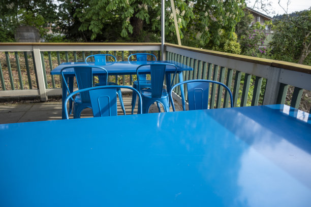 在一家餐厅的户外露台上，明亮的蓝色椅子聚集在一张蓝色的桌子周围图片下载
