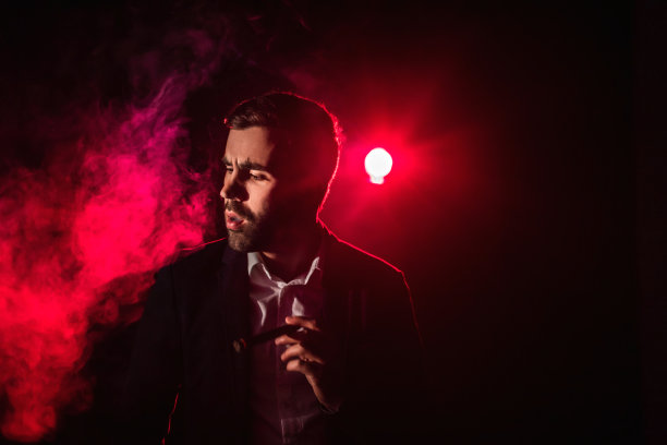 一名男子在黑暗中吸烟的照片。图片下载