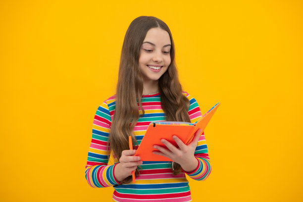在孤立的背景上拿着复印本摆姿势的女生。文法学校的文学课。智力儿童读者。图片下载