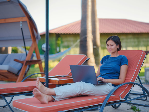 年轻的女商人在酒店泳池边的电脑旁工作。图片下载