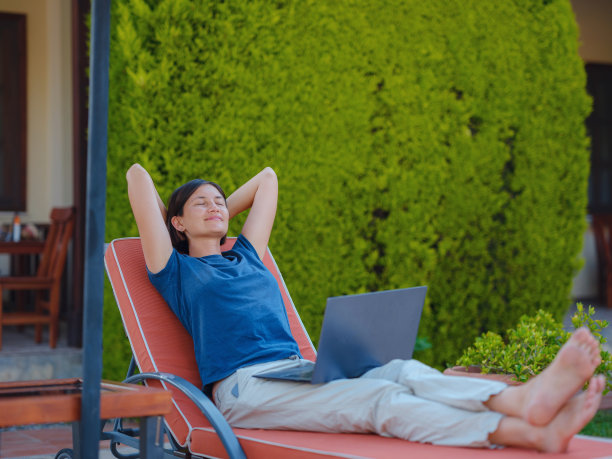 年轻的女商人在酒店泳池边的电脑旁工作。图片下载