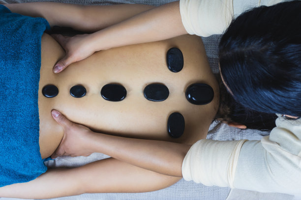 俯视放松年轻的褐发拉丁女人在温泉沙龙得到热石按摩图片下载