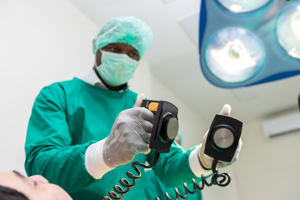 医生正在医院里使用除颤器来挽救病人的生命。心肺复苏术。用除颤器拯救生命。男外科医生的手在医院拿着除颤器图片下载