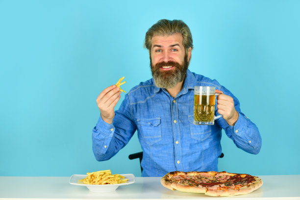 良好的食欲。还是饿。啤酒和食物。晚餐在酒吧。饥饿的人要吃披萨薯条和喝啤酒。披萨店的餐厅。快乐的男人，留着胡子的嬉皮士吃披萨。披萨派对的概念图片下载