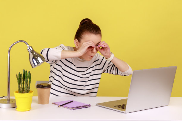 女人牵着手靠近眼睛，用望远镜看笔记本电脑屏幕，发现一些惊讶的东西。图片下载