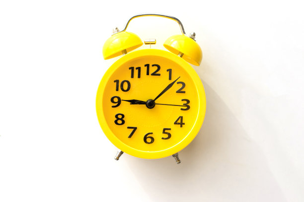 黄色闹钟躺在白色的桌子上，俯视图图片下载