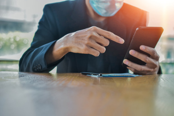 商人在口罩上使用手机智能手机集中在手机上进行在线工作图片下载