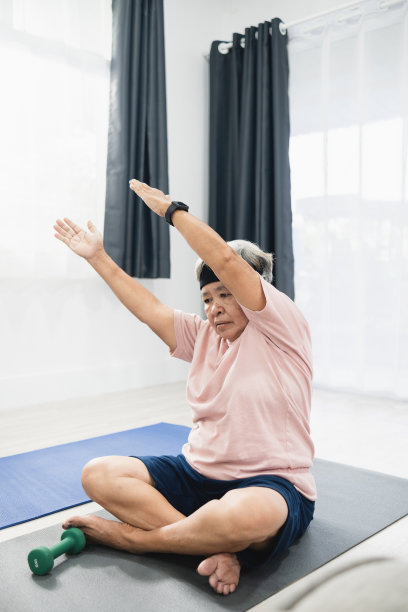 居家健身理念，亚洲老年妇女在客厅举起双手锻炼身体。垂直的照片。图片下载