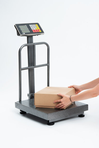 正在称包裹的妇女。包裹尺度孤立在白色背景。图片下载