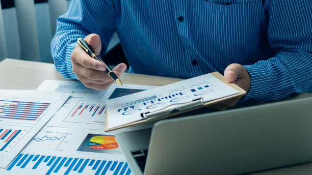 女商人持有文件与财务统计，库存照片，讨论和数据分析，图表和图形与笔记本电脑。金融概念图片下载