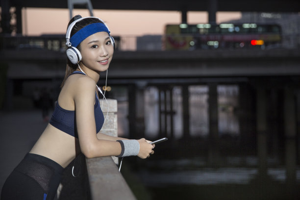 年轻的东亚妇女使用手机在清晨的体育训练在城市街道-股票的照片图片下载