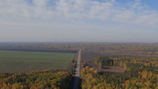 道路之间黄色和绿色的秋天森林和田野在乌拉尔图片下载