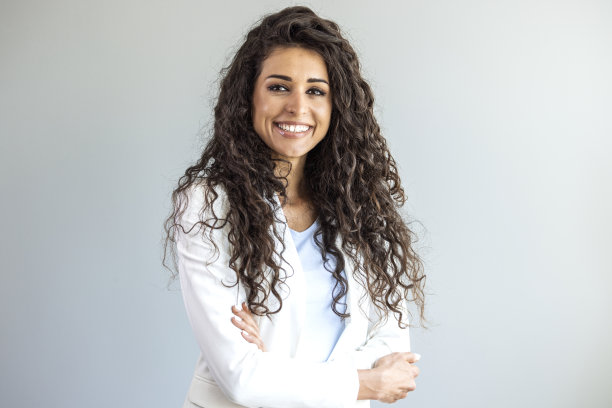 年轻微笑的女人的肖像看着相机与交叉的胳膊。图片下载