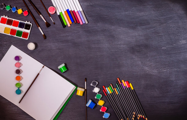 打开笔记本，在黑色背景上放置特克斯和文具配件。图片下载