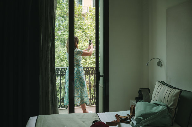 年轻女子在阳台上用智能手机图片下载