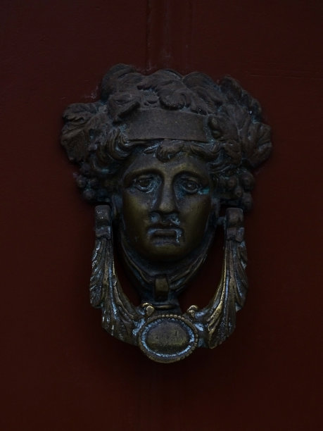 酒红色木门上狄俄尼索斯头形状的门环图片下载