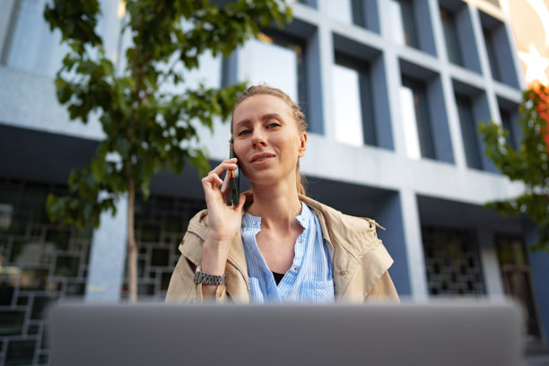 年轻漂亮的女人坐在街上的长凳上用笔记本电脑工作图片下载