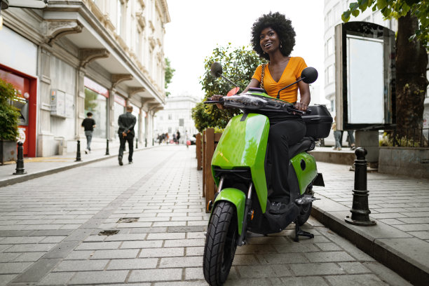 年轻的非洲裔美国妇女骑着绿色摩托车在城市的肖像图片下载