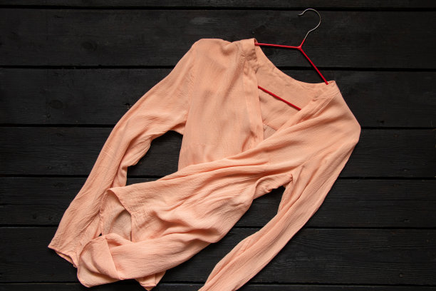 黑色木桌上放着一件轻薄的丝绸女式衬衫，衣服图片下载