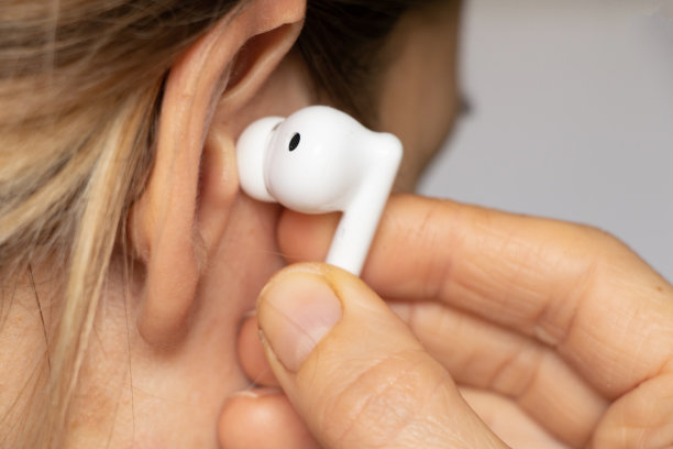 无线白色耳机在女孩耳边特写，戴着耳机听音乐，无线耳机图片下载