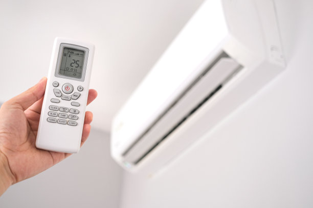 用遥控器打开的手卧室里的空调被冷却到摄氏25度。健康理念和节能图片下载