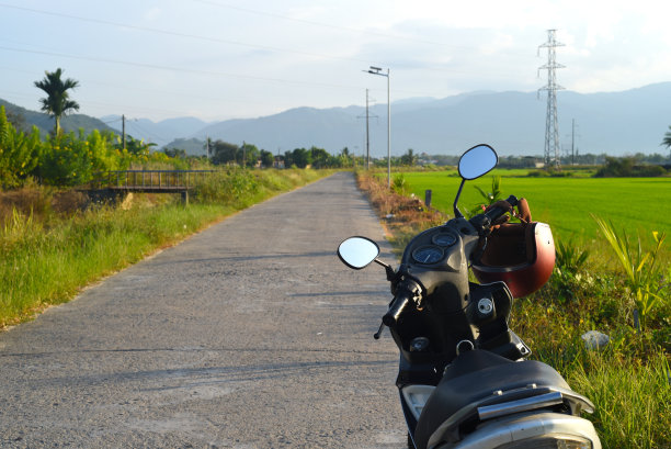 一辆摩托车行驶在越南稻田之间的路上图片下载