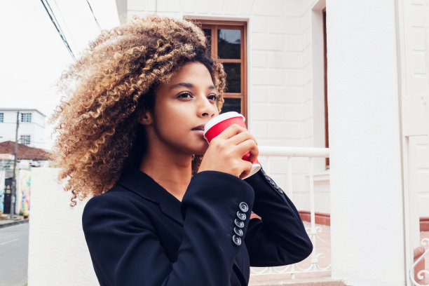 美丽优雅的非洲商业妇女喝咖啡在城市微笑户外享受图片下载