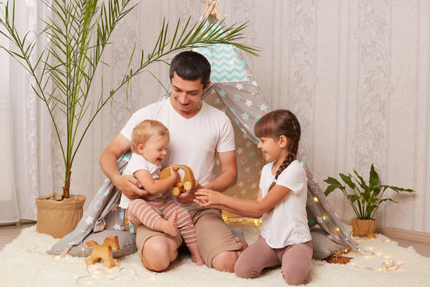 快乐的父亲和他的小女儿在家里的儿童房间的棚屋里玩耍，玩玩具，度过快乐的时光。图片下载